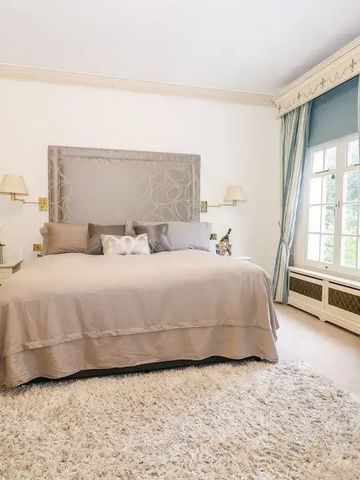 Schlafzimmer mit großem Bett, Teppich und eleganten Vorhängen.