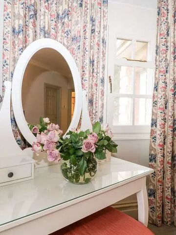 Eleganter Schminktisch mit Spiegel und Blumenbouquet in klassischem Zimmer.