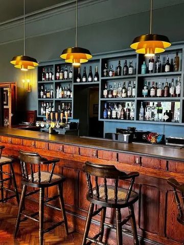 Gemütliche Hotelbar mit Holztheke und beleuchtetem Spirituosenregal