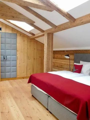 Geräumiges Dachzimmer mit Holzwänden und roten Bettdecken
