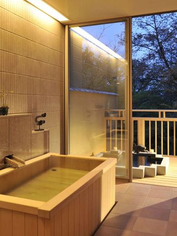 Holzbadewanne mit Blick auf einen Balkon und Natur