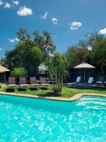 Einladender Pool mit Liegestühlen und Sonnenschirmen umgeben von Natur