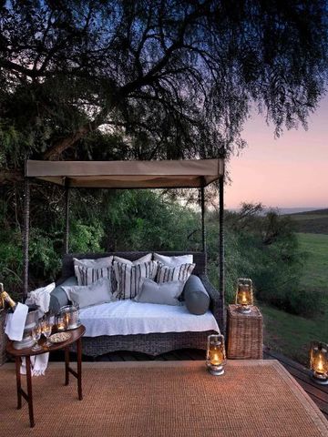 Outdoor-Lounge mit Sofa unter einem Baum bei Sonnenuntergang