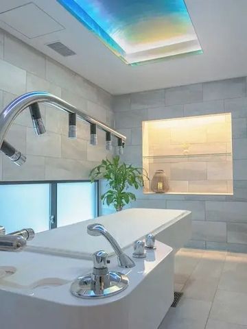 Spa-Raum mit Wasserfall-Dusche und beruhigender blauer Deckenbeleuchtung.