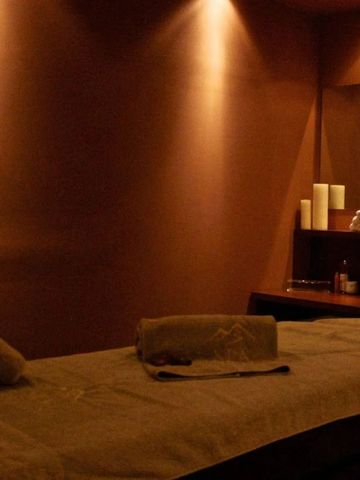Gedimmter Spa-Raum mit Massageliege und sanfter Beleuchtung.