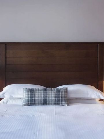 Elegantes Schlafzimmer mit Holzbetthaupt und Lampen auf Nachttischen