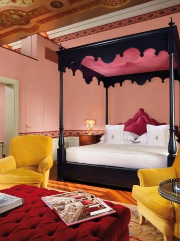 Luxuriöses Zimmer mit Himmelbett und eleganten Möbeln in warmen Tönen.