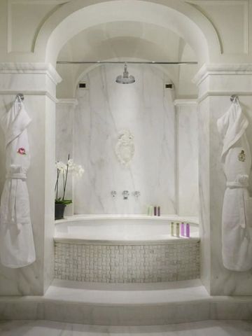 Elegantes Marmorbad mit dekorativer Skulptur und Orchidee