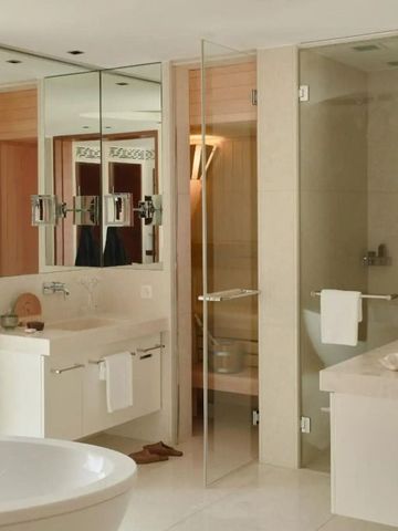 Helles Badezimmer mit großer Badewanne und Glaselementen.