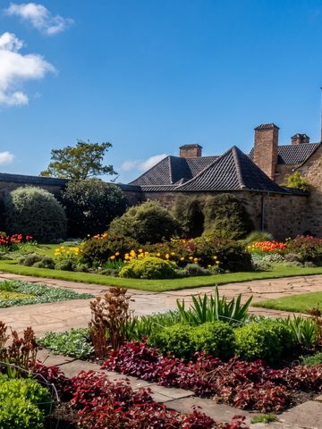 Große Gartenanlage des Hotels mit gepflegten Blumenbeeten und historischem Charme