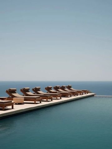 Anordnung von Liegestühlen am Pool mit Blick auf das Meer