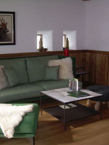 Gemütliche Wohnzimmeratmosphäre mit grüner Couch und Holzwänden