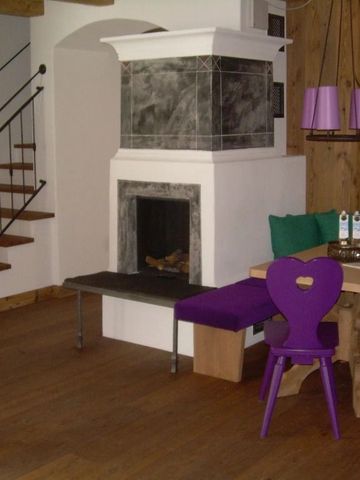 Essbereich mit traditionellem Kamin, Holzboden und farbigen Stühlen