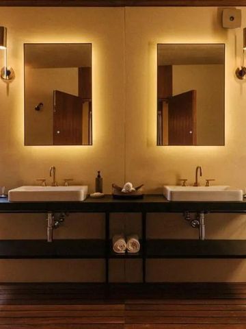 Modernes Badezimmer mit Doppelwaschbecken und beleuchteten Spiegeln