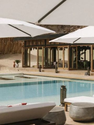 Moderner Poolbereich mit Liegen und Sonnenschirmen vor einer Glasfassade