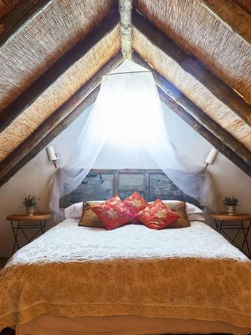 Gemütliches Schlafzimmer unter einem Strohdach mit Tageslicht und eleganten Details
