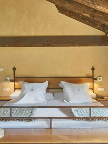 Gemütliches Doppelbett im Hotelzimmer mit Holzbalken und Steinwänden