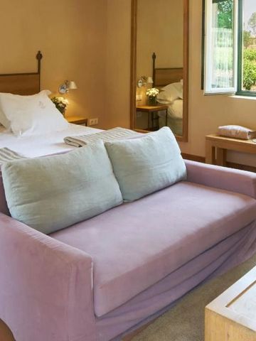 Gemütliches Hotelzimmer mit Sofa, Doppelbett und Blick auf grüne Umgebung