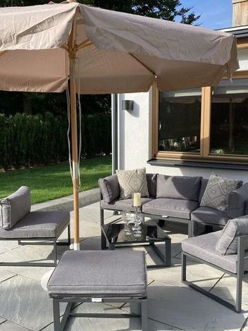 Terrasse mit grauen Sitzmöbeln und großem Sonnenschirm