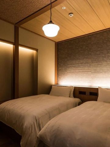 Hotelzimmer mit zwei Einzelbetten und stilvoller minimalistischer Beleuchtung