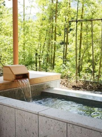 Privater Outdoor-Onsen aus Stein inmitten von Bambus