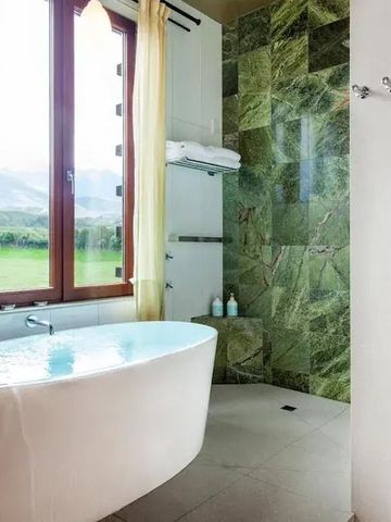 Elegantes Badezimmer mit grüner Fliesenwand und freistehender Wanne