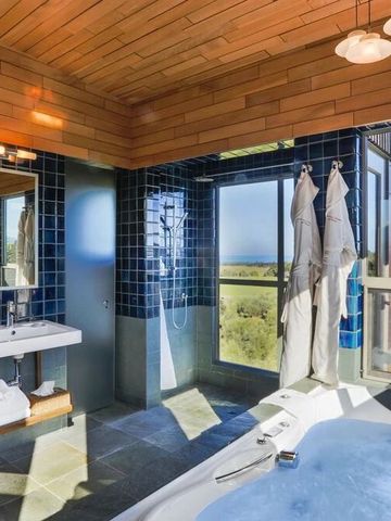 Luxuriöses Badezimmer mit freistehender Badewanne und Blick auf die Natur