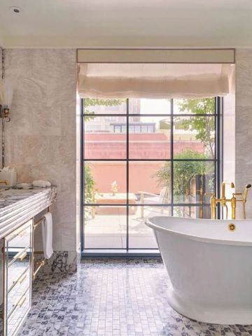 Geräumiges Badezimmer mit freistehender Badewanne und Marmordetails