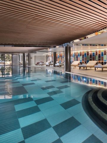 Luxuriöser Innenpool mit Mosaikfliesen und gemütlichen Liegen
