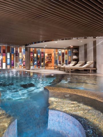 Luxuriöser Innenpoolbereich mit Liegen und kunstvoller Deckengestaltung im Hotel