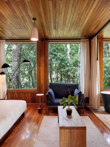 Elegantes Zimmer mit Holzwänden, großer Fensterfront und freistehender Badewanne