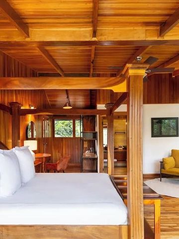 Zimmer mit Holzakzenten, Himmelbett und Sitzbereich in warmen Farben