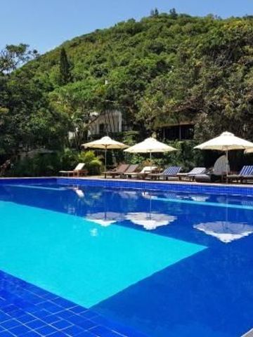 Klarer blauer Pool mit Liegestühlen und Blick auf bewaldete Hügel