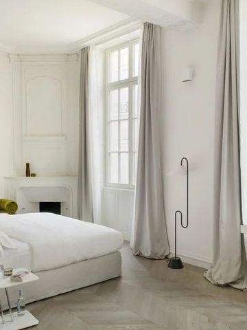 Stilvoll eingerichtetes Zimmer mit großen Fenstern und Vorhängen.