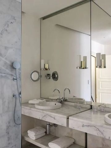 Modernes Badezimmer mit Marmordetails und großer Spiegelwand