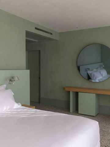 Minimalistisch eingerichtetes Hotelzimmer mit grünem Farbschema und großem Spiegel