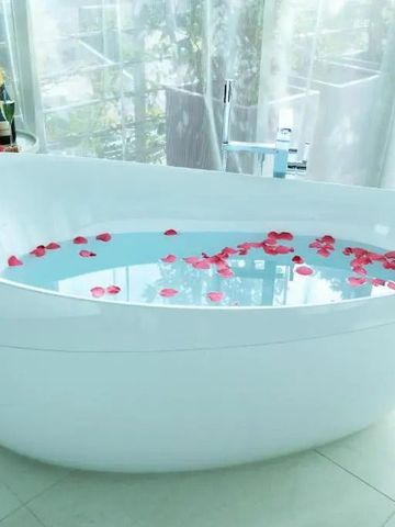 Freistehende Badewanne mit Rosenblättern und Sekt