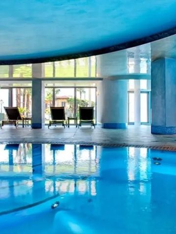 Indoor-Pool mit stilvoller, blauer Beleuchtung und bequemen Liegestühlen