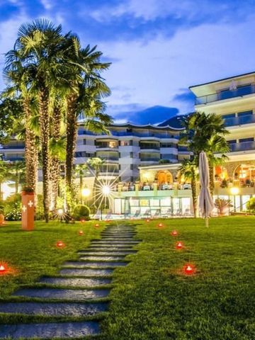 Beleuchteter Garten mit Palmen vor einem mehrstöckigen Hotelgebäude