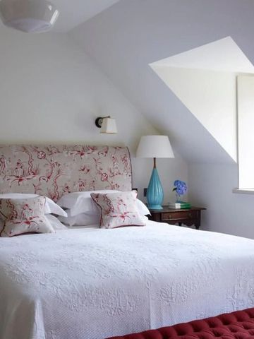 Helles Schlafzimmer mit weißer Bettwäsche und einem großen Fenster