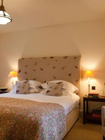 Komfortables Schlafzimmer mit romantischer Beleuchtung und floralem Bettkopf