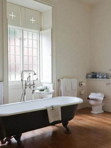 Geräumiges Badezimmer mit freistehender Badewanne und großen Fenstern im Hotel Endsleigh.