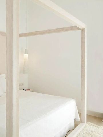 Modernes Hotelzimmer mit Himmelbett in neutralen Tönen und weißem Vorhang