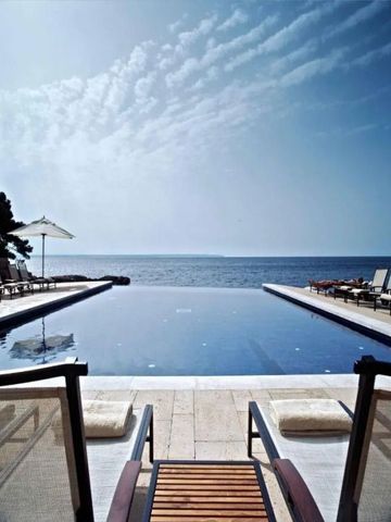 Infinity-Pool mit Blick auf das Meer und komfortablen Liegestühlen
