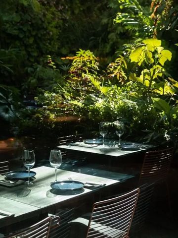 Gartenrestaurant mit Tischgedecken und üppiger Vegetation