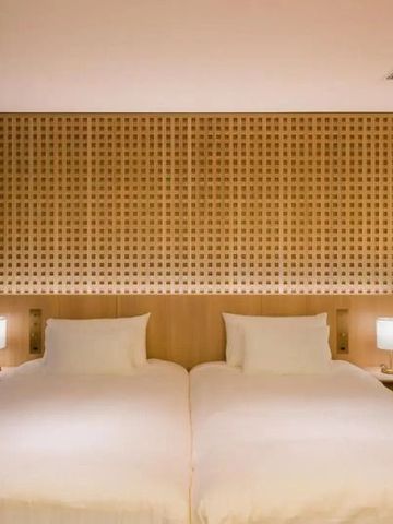Minimalistisch gestaltetes Hotelzimmer mit zwei Einzelbetten, warmem Licht und Holzdetails