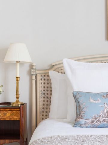 Elegantes Schlafzimmer mit weißer Bettwäsche und blauem Zierkissen