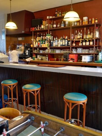 Gemütliche Hotelbar mit Holzhockern und gut bestücktem Regal im Hintergrund