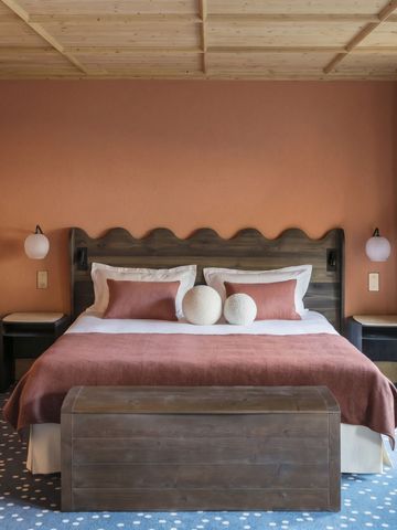 Gemütliches Hotelzimmer mit Doppelbett und rustikalem Holzdach in warmem Farbton