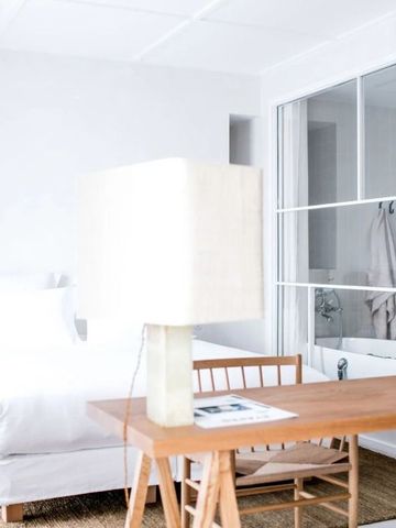 Modern eingerichtetes Zimmer mit Schreibtisch, Lampe und Einblick ins Badezimmer
